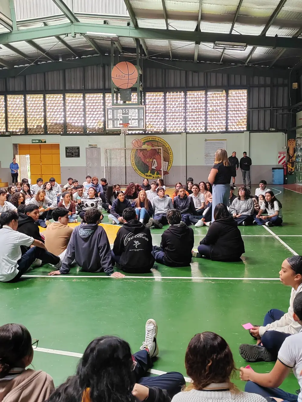 Coach Wen conversando con un grupo de estudiantes de secundaria en un gimnasio